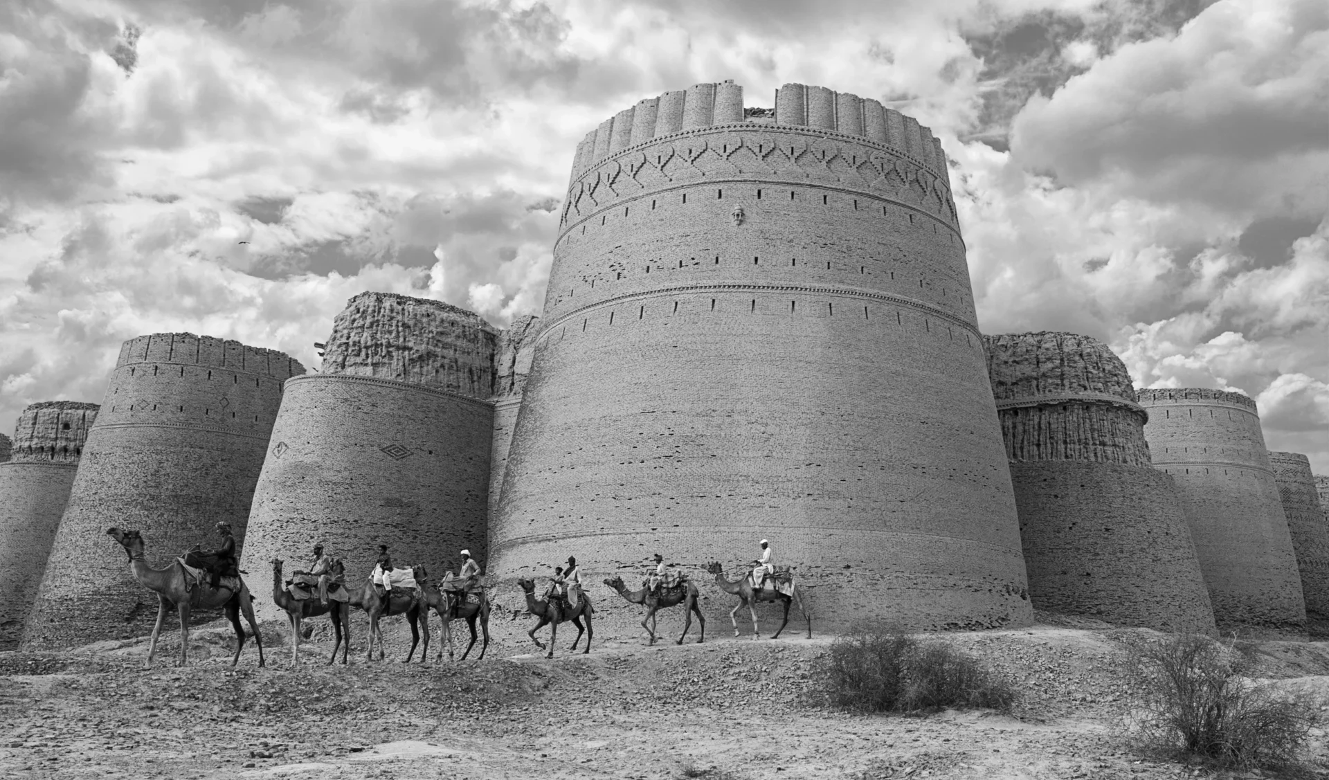 A group of men riding horses near large towers.