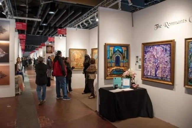 A group of people standing around in an art gallery.